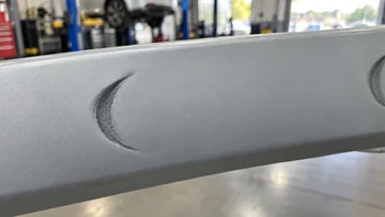 Close-up of a dark crescent-shaped casting mark on a light automotive trim piece.